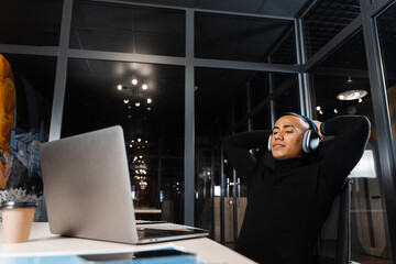 Sleepy and tired asian man working overtime at laptop in office and taking break.