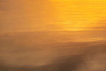 Ripples and small golden waves on the water. Water surface in sunset time. Copy space
