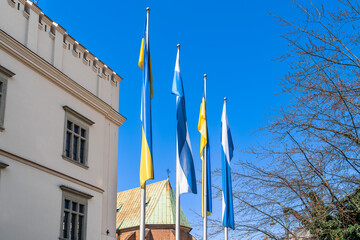 Flags of Ukraine and Krakow on a sunny day against a blue sky and building walls in early spring....