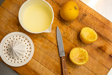 Wooden cutting board with knife, lemon juice and lemons