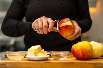 Applepie preparation peeling apples with ingredients in the foreground