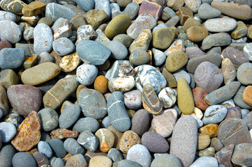 sea pebble beach with multicoloured stones, transparent waves with foam, on a warm summer day