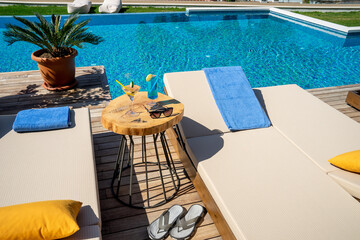Refreshing cocktail  glass on natural wood coffee table. Swimming and sunbathing in the hotel pool, vacation travel concept.