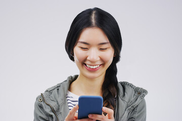 The smartest way to stay in touch. Studio shot of a young woman using a mobile phone against a grey background.