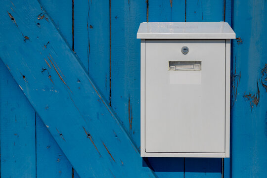 Selective focus of white mailbox hanging on blue wooden door, Outdoor post box with wood background.
