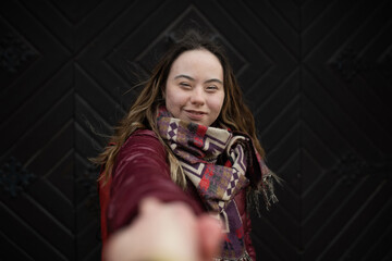 Young woman with Down syndrome looking at camera on black background