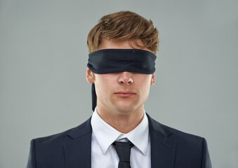 Going blindly into the deal.... Cropped view of a young businessman with his eyes blindfolded.