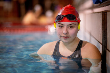 Young woman with Down syndrome in swimming pool looking at camera