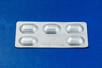 Blister or pack of five tablets or pills. The concept of five working days. Dark blue background.