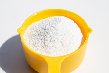 Detergent powder with measuring spoon for clothes washing. Laundry concept.