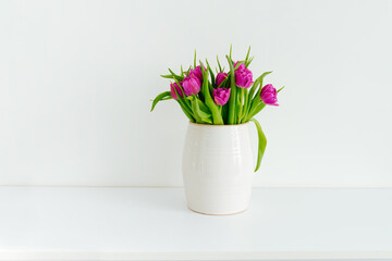 Bouquet of purple tulips in a vase on a white background