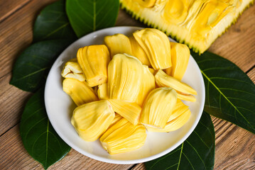 Ripe jackfruit peeled tropical fruit fresh from jackfruit tree, jackfruit on white plate with leaf on wooden background