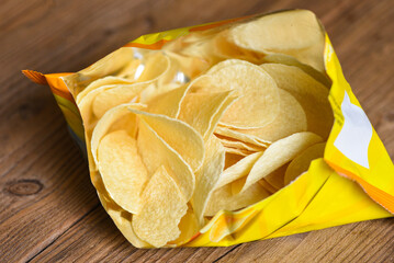 Potato chips on wooden background, Potato chips is snack in bag package wrapped in plastic ready to eat and fat food or junk food