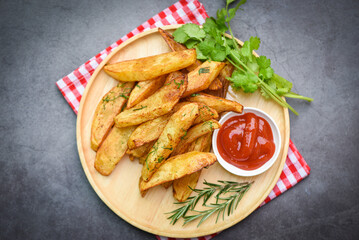 Potato wedges on wooden plate with rosemary herb coriander and tomato ketchup sauce, Cooking french fries or fry potatoes