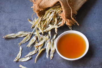 fish sauce on white bowl and small dried fish in the sack, fish sauce obtained from fermentation...
