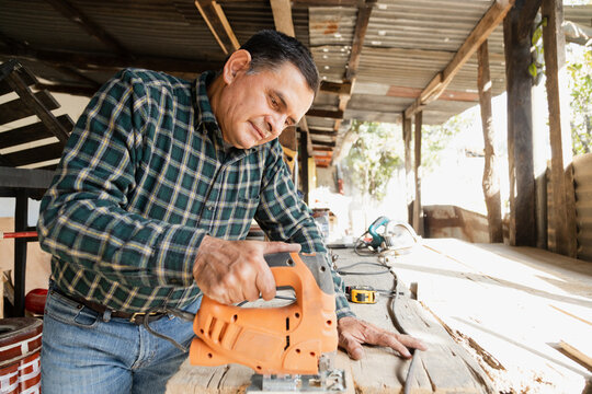 Happy Carpenter Working With Carpentry Tools - Smiling Hispanic Man Doing Carpentry In A Wood Workshop