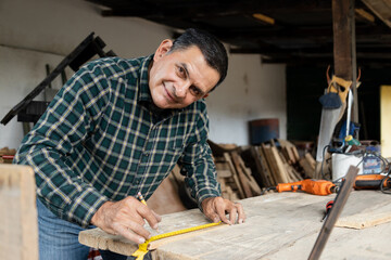 Hispanic carpenter working in his workshop - man working with carpentry tools - happy carpenter working