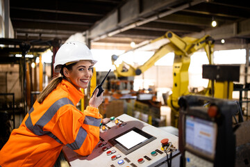 Female worker in safety equipment controlling industrial manufacturing process and parts assembly in factory.