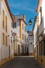 Fototapeta na wymiar The view of narrow paved street of Evora with the cozy white houses. Evora. Alentejo. Portugal