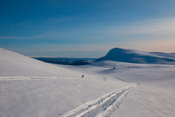 A winter ski and snowmobile trail downhill towards an emergency shelter. Kungsleden trail between Hemavan and Ammarnas, Lapland, Sweden, early March.