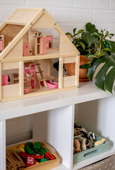 Montessori material. White shelves in a room with neatly arranged toys.