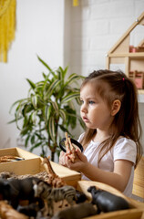 Montessori material. Toddler girl explores wild animals through play.