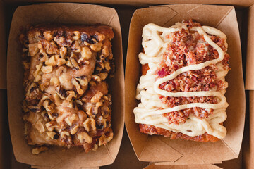 Walnut cinnamon roll and maple bacon cinnamon roll boxes close up, flat lay
