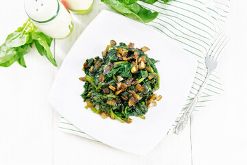 Spinach fried with onions in plate on board top