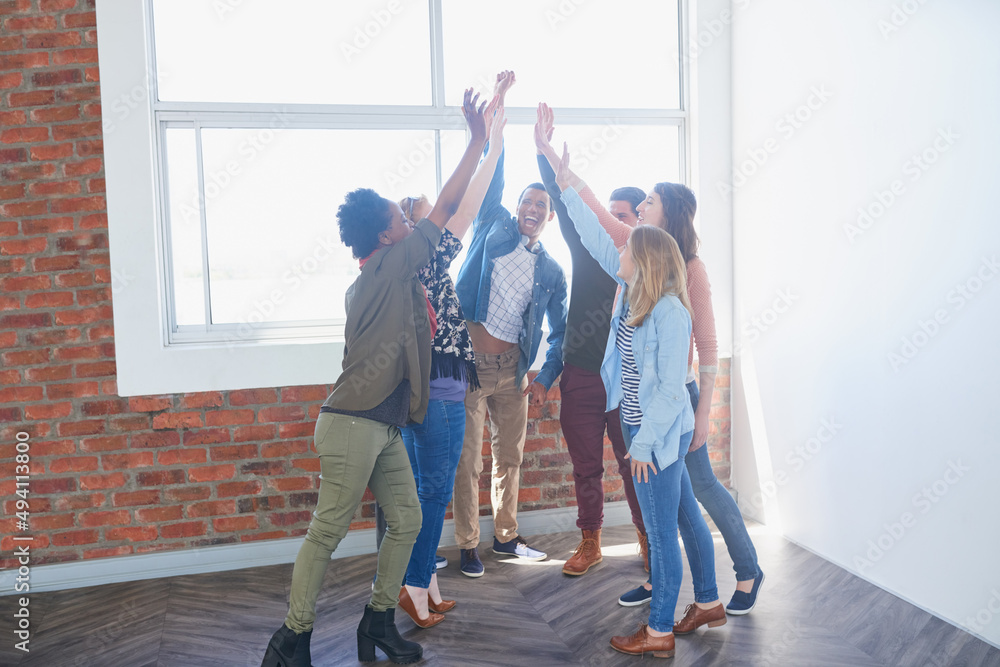 Poster achieving success together. shot of a group of university students high fiving one another during cl