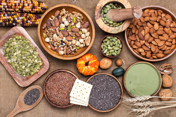 selection of healthy and clean food: seeds, superfoods, nuts, beans, biscuits on burlap background.