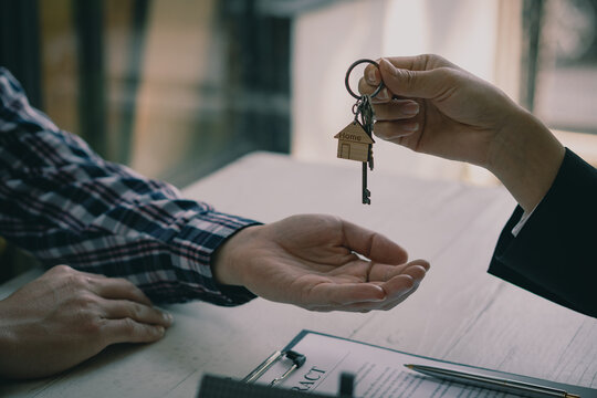 The house sales representative holds the keys and the car with paperwork. home loan Pen insurance form on the table Financing a home loan or deposit interest rates business and finance concept