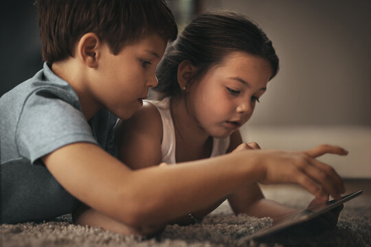 Kid friendly entertainment is just an app away. Shot of an adorable brother and sister using a digital tablet together on the floor at home.