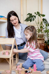 Montessori material. Home education. Mom and daughter are learning dollhouse furniture.