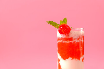 Strawberry cocktail with cream.Berry smoothies. Pink cocktail and cream in a transparent glass goblet with strawberries and sprigs of mint on a pink background.Delicious and healthy Drink 