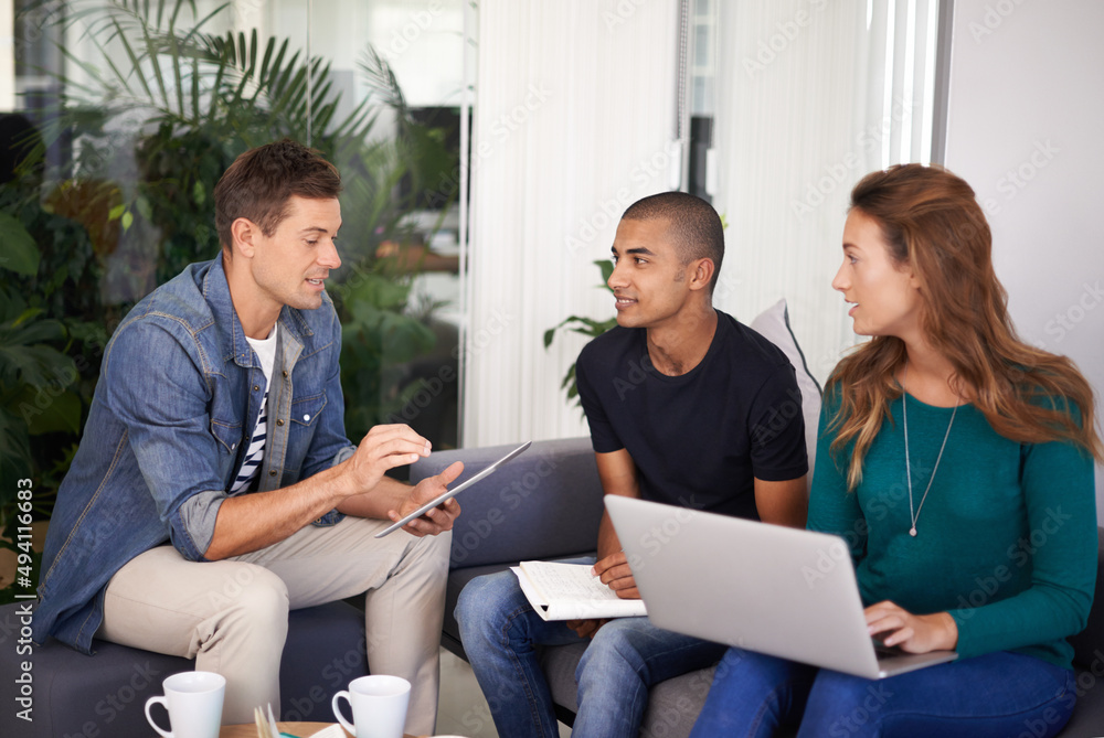 Poster Brainstorming some ideas. A team of young business professionals using technology in an informal meeting.