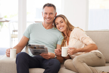 Sharing the morning paper. Portrait of a happily married couple reading the newspaper on their sofa.