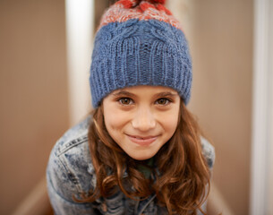 Time for some vacation fun. Shot of a young girl posing in her woolen hat indoors.