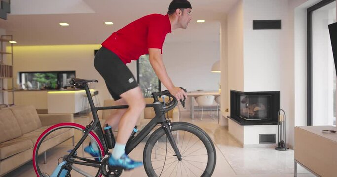 Man cycling on the machine trainer he is exercising in the home.Playing online bike racing game during coronavirus covid19 lockdown. New normal concept.