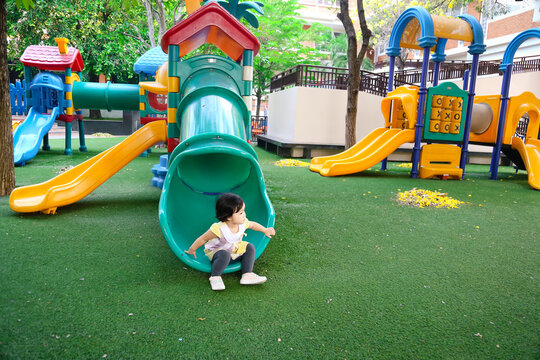 2 yeas old Asian baby girl playing at the playground alone. 