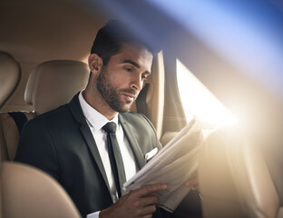 Catching up on the latest news. Cropped shot of a handsome young businessman reading the paper...