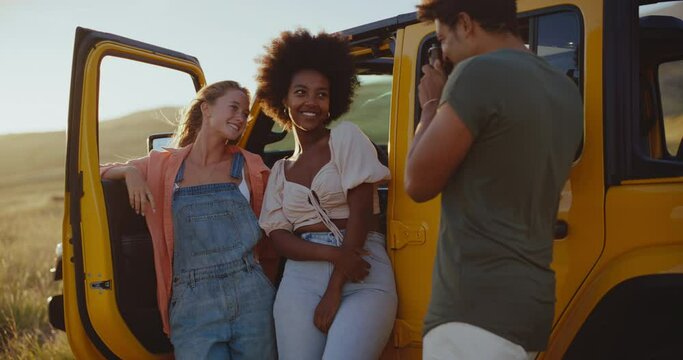 Epic road trip, group of three best friends laughing and taking pictures with vintage camera on epic road trip