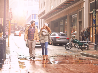 Enjoying a winter walk together. Shot of a happy young couple walking through an urban area together.