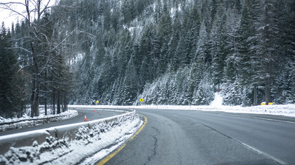 Turning winding divided highway road at winter dangerous condition with snow and ice and mountain...