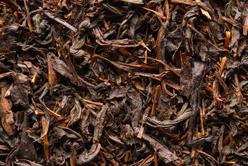 Black large-leaf tea as abstract background. Texture of dry black tea leaves. Dark background. Macro black tea leaf