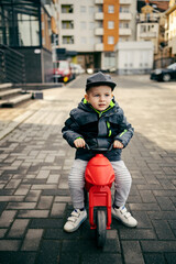 A little boy riding a tricycle fast on the street.