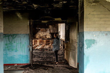 Destroyed building. Burnt building . Broken windows with ash . Woman in a destroyed burnt building