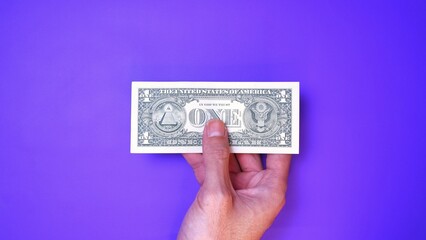 Businessman's hand holding American Dollar Banknotes, isolated on a purple background. Business Investment Economy Saving Loan Income Money and Finance concept. One Dollar, 1 USD. Prosperity concept.