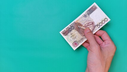 Indonesian Rupiah the official currency of Indonesia. Man's hand is making a payment. Male hand...