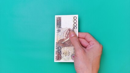 Indonesian Rupiah the official currency of Indonesia. Man's hand is making a payment. Male hand...