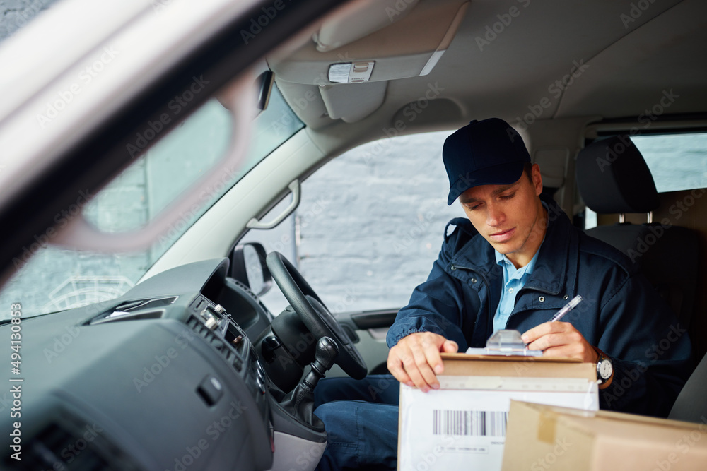 Poster packages that are delivered need to be marked off. cropped shot of a handsome young delivery man usi